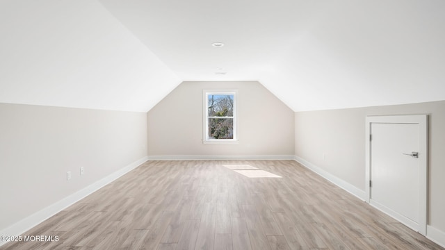 additional living space with light wood-style floors, baseboards, and vaulted ceiling