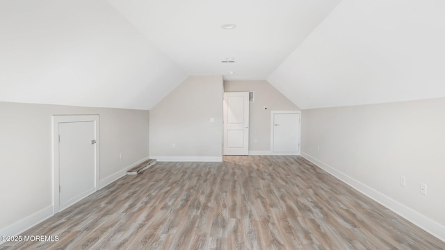 additional living space with lofted ceiling, light wood-type flooring, and baseboards