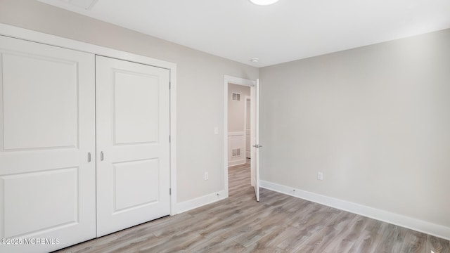 unfurnished bedroom with a closet, visible vents, light wood finished floors, and baseboards