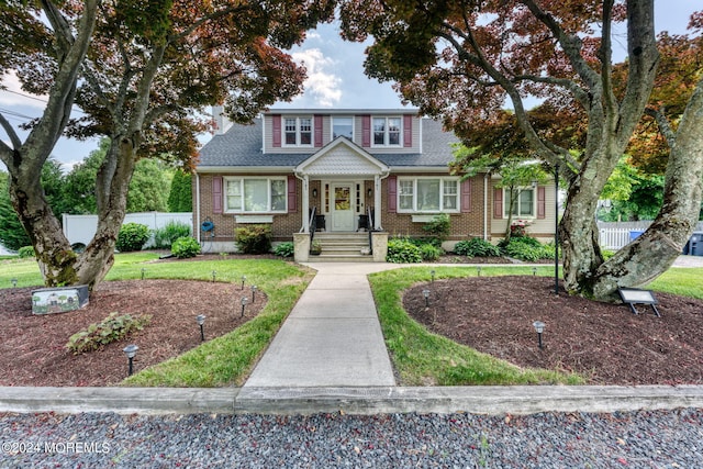 view of front of house featuring a front lawn, fence, and brick siding