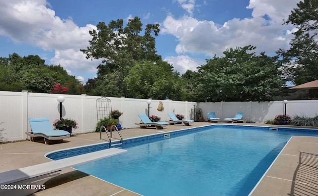 view of pool featuring a diving board, a fenced in pool, a fenced backyard, and a patio area