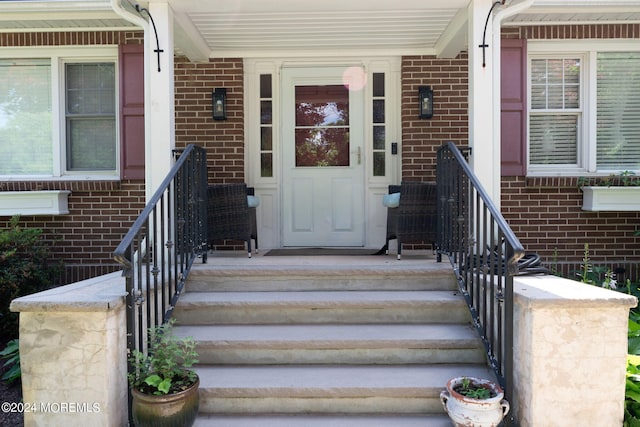 entrance to property featuring covered porch and brick siding