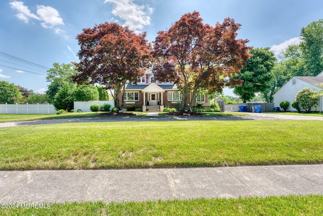 obstructed view of property with a front lawn and fence