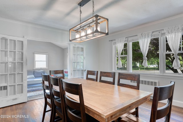 dining area with radiator, crown molding, baseboards, and wood finished floors