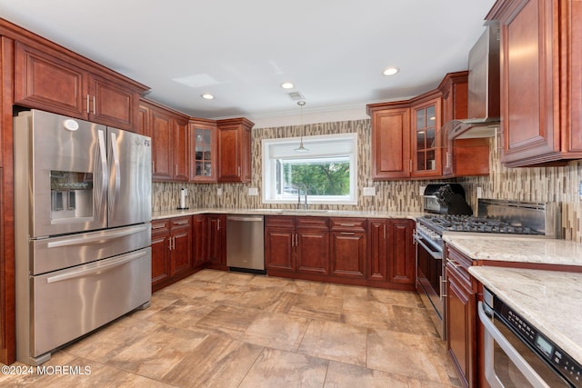 kitchen featuring a sink, light stone counters, tasteful backsplash, stainless steel appliances, and wall chimney exhaust hood