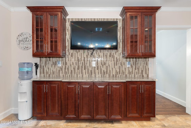 bar featuring decorative backsplash, a bar, baseboards, and ornamental molding