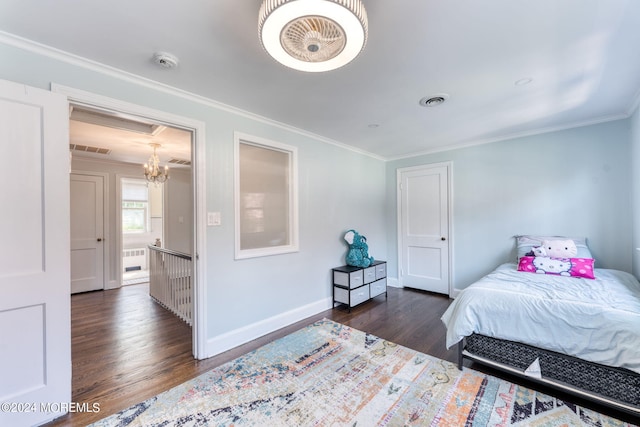 bedroom with crown molding, wood finished floors, visible vents, and baseboards