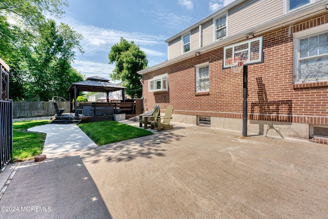 view of property exterior with a gazebo, a patio, brick siding, and fence