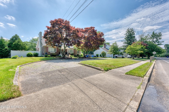 view of property hidden behind natural elements featuring a front yard and fence