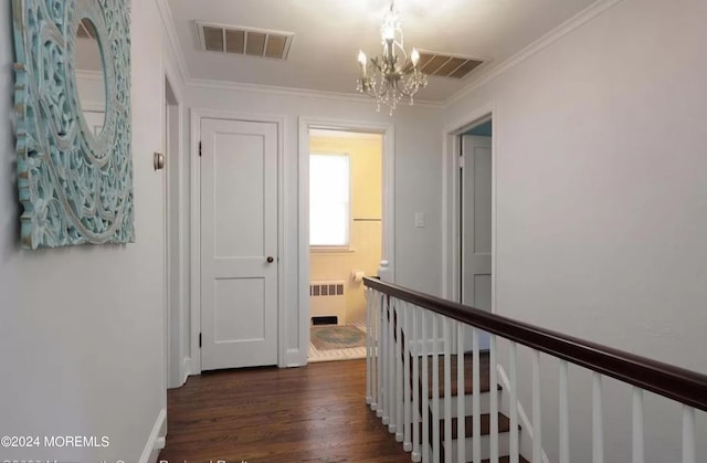 hallway with an upstairs landing, visible vents, radiator heating unit, and ornamental molding