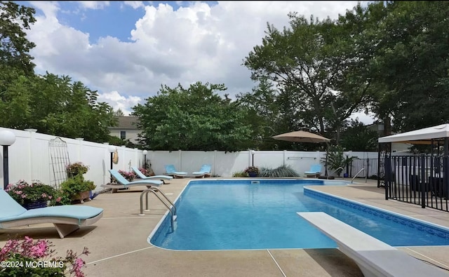 view of pool featuring a diving board, a fenced in pool, a patio, and a fenced backyard