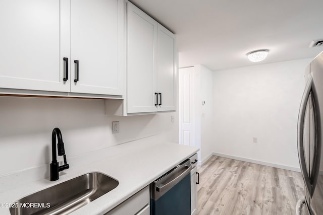 kitchen featuring a sink, white cabinetry, light countertops, appliances with stainless steel finishes, and light wood-type flooring