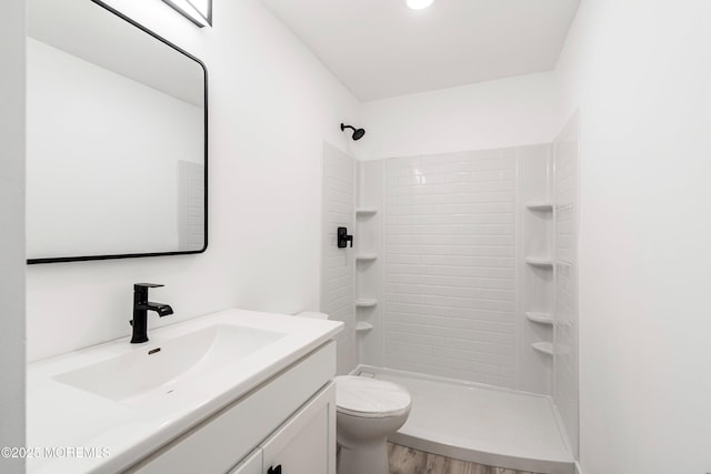 full bathroom with tiled shower, vanity, toilet, and wood finished floors