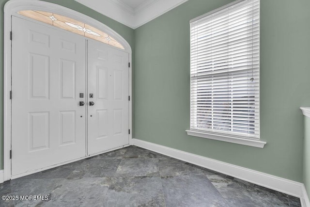 foyer entrance with ornamental molding and baseboards