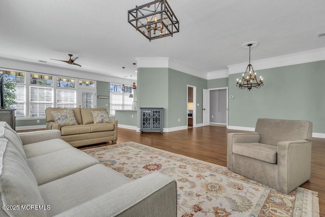 living room with ceiling fan with notable chandelier, crown molding, baseboards, and wood finished floors