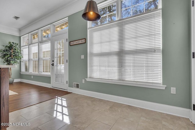 interior space with ornamental molding, tile patterned flooring, visible vents, and baseboards