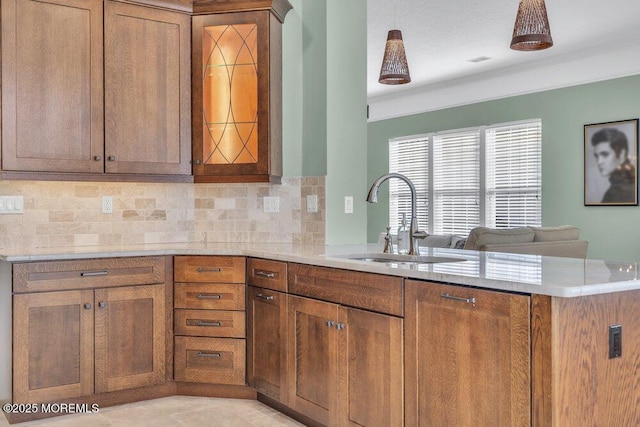 kitchen with a peninsula, brown cabinetry, a sink, and light countertops