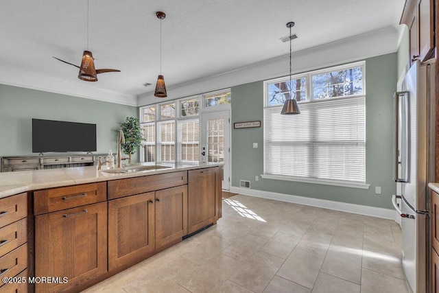 kitchen featuring visible vents, brown cabinetry, decorative light fixtures, crown molding, and a sink