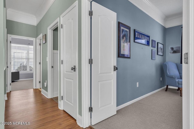 corridor with baseboards, carpet, wood finished floors, and crown molding