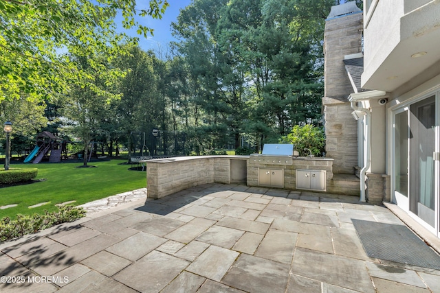 view of patio / terrace featuring a trampoline, playground community, grilling area, and an outdoor kitchen