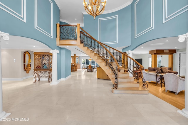 stairway with a chandelier, ornate columns, and ornamental molding