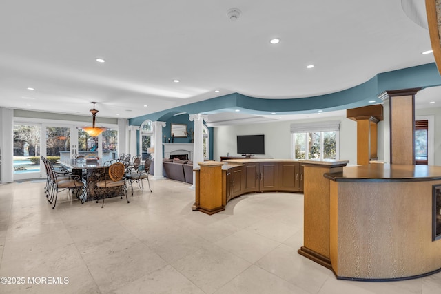 kitchen featuring decorative columns, a fireplace, open floor plan, and plenty of natural light