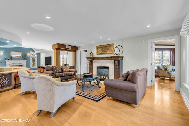 living room featuring recessed lighting, visible vents, light wood-style flooring, and a high end fireplace