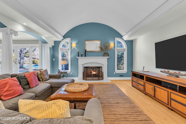 living area with baseboards, plenty of natural light, light wood-style flooring, and ornate columns