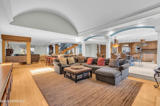 living area featuring stairs, decorative columns, recessed lighting, and light wood-type flooring