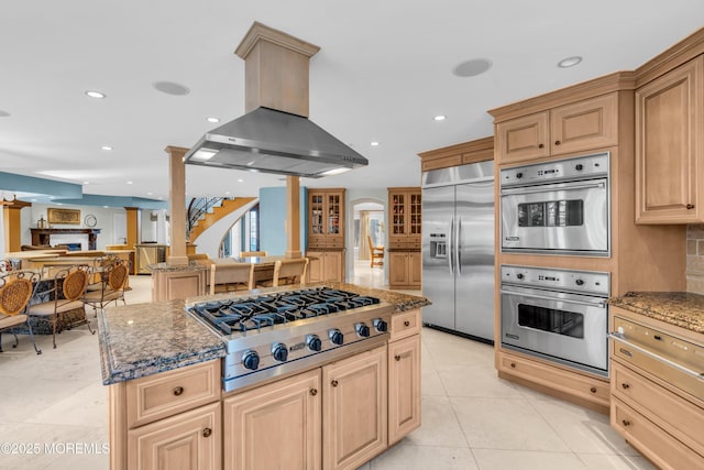 kitchen with light tile patterned floors, stone counters, appliances with stainless steel finishes, and island exhaust hood