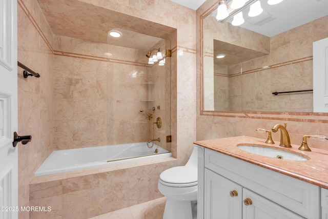 bathroom featuring toilet, vanity, decorative backsplash, tile walls, and tiled shower / bath