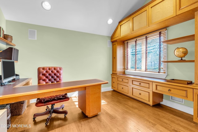 office space featuring baseboards, visible vents, built in study area, light wood-style flooring, and vaulted ceiling