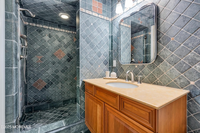 full bathroom with a shower stall, vanity, and tile walls