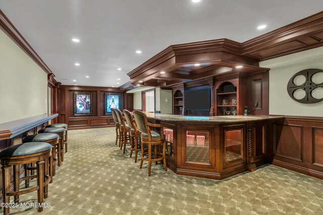 bar with crown molding, light colored carpet, wainscoting, recessed lighting, and a bar