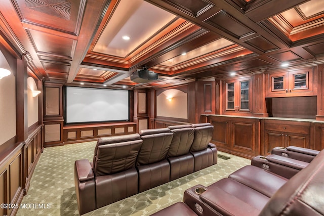 home theater room featuring coffered ceiling, crown molding, carpet flooring, and a decorative wall