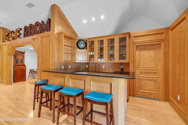 kitchen featuring lofted ceiling, dark countertops, and light wood finished floors