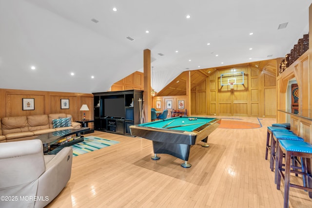 playroom with lofted ceiling, wooden walls, a decorative wall, and light wood finished floors