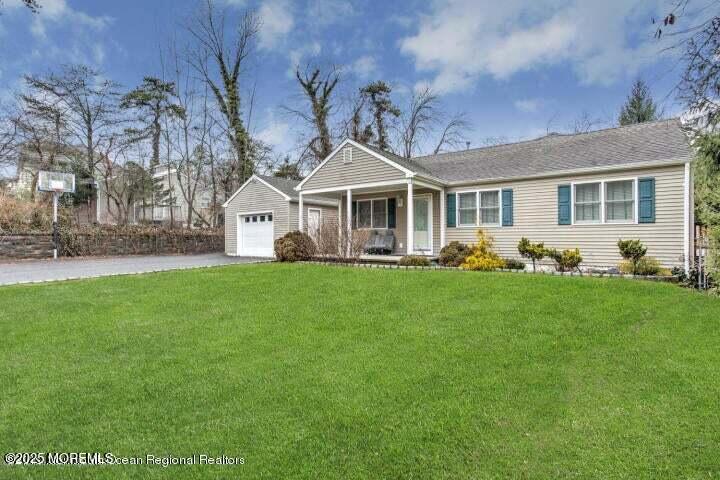 ranch-style house with a garage, driveway, a porch, and a front lawn