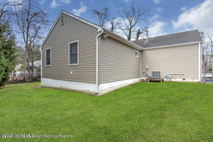 view of home's exterior with a yard, central AC, and fence