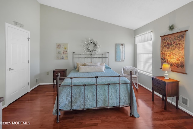 bedroom featuring vaulted ceiling, wood finished floors, visible vents, and baseboards