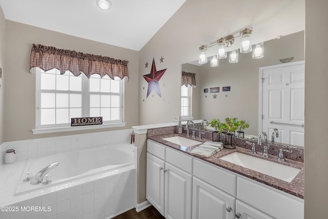 full bathroom featuring a garden tub, double vanity, and a sink