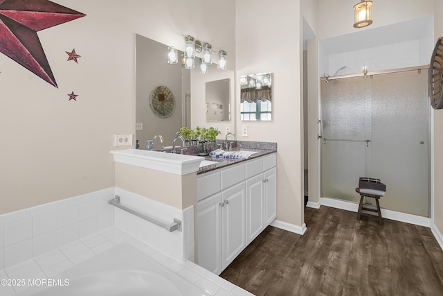 full bathroom with a washtub, wood finished floors, a sink, a shower stall, and double vanity