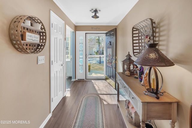 doorway featuring baseboards, ornamental molding, and wood finished floors