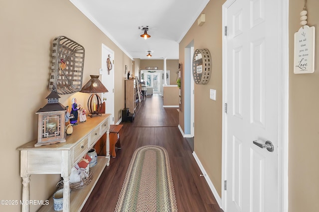 corridor with dark wood-style floors, crown molding, and baseboards