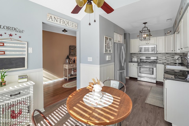 kitchen featuring a wainscoted wall, appliances with stainless steel finishes, a sink, and white cabinetry