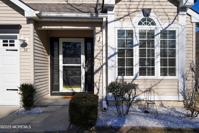 property entrance with a garage and a shingled roof