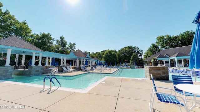 community pool with a patio area, fence, and a pergola