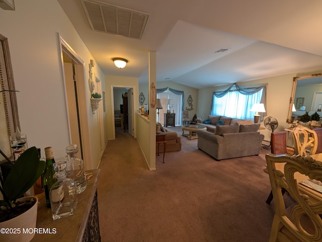 carpeted living area with visible vents and vaulted ceiling