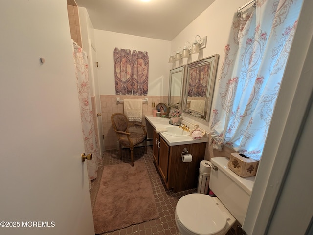 full bath with tile walls, toilet, wainscoting, vanity, and tile patterned floors