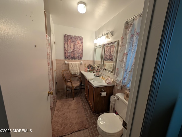 full bathroom with tile walls, toilet, wainscoting, vanity, and tile patterned flooring